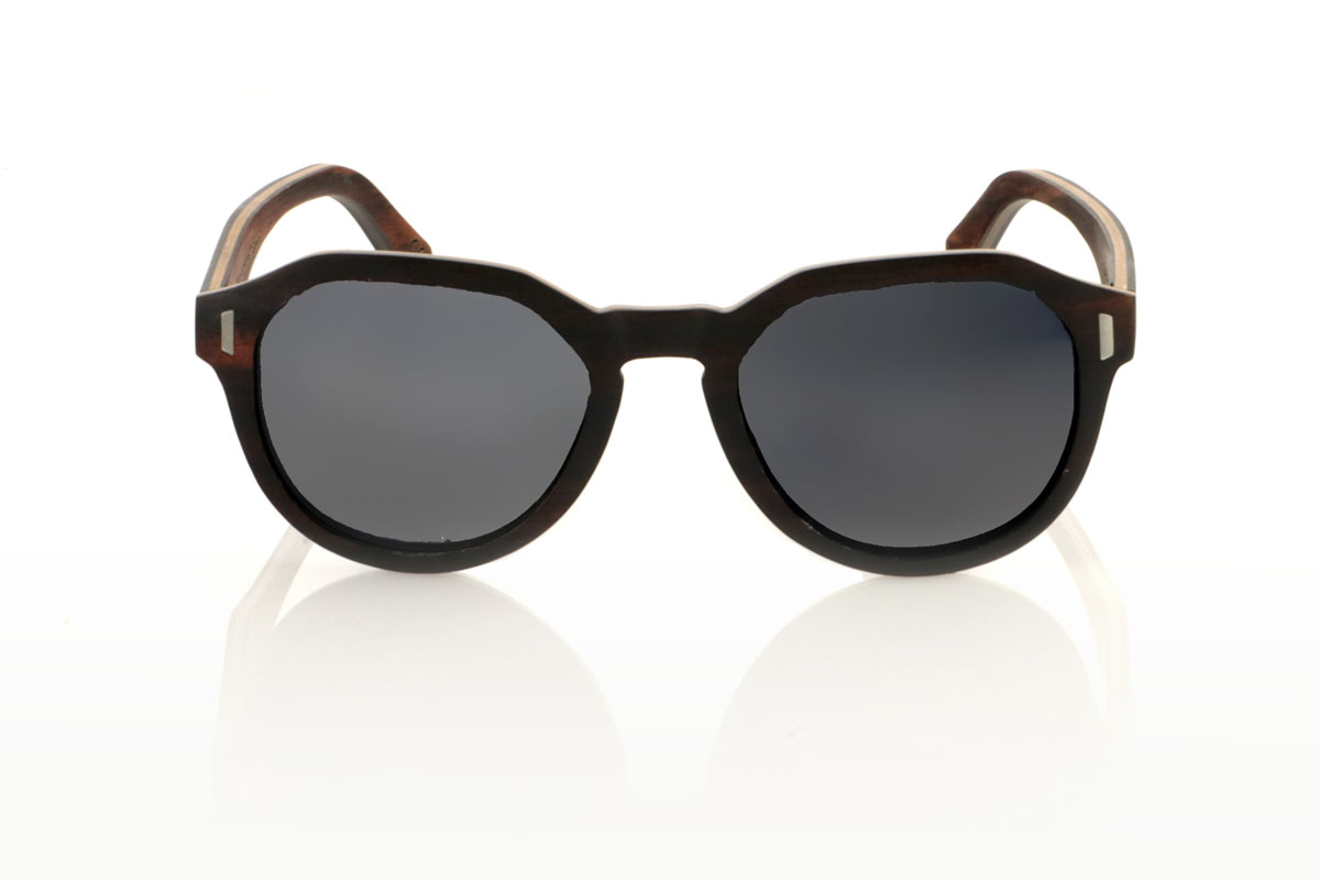 Wood eyewear of Ebony IZARO. IZARO wooden sunglasses are an expression of style and craftsmanship, made entirely of laminated ebony wood both outside and inside, with an intermediate layer of maple wood that provides a clear and striking contrast. The distinctive black and brown grain of the ebony is perfectly complemented by the distinctive hexagonal shape on the brow, while the silver metallic inlays on the sides add a touch of elegance and sophistication. With measurements of 145x50 and a caliber of 51, the IZARO are presented as a perfect option for those looking to stand out with a unique accessory that combines the natural beauty of wood with an innovative design. for Wholesale & Retail | Root Sunglasses® 